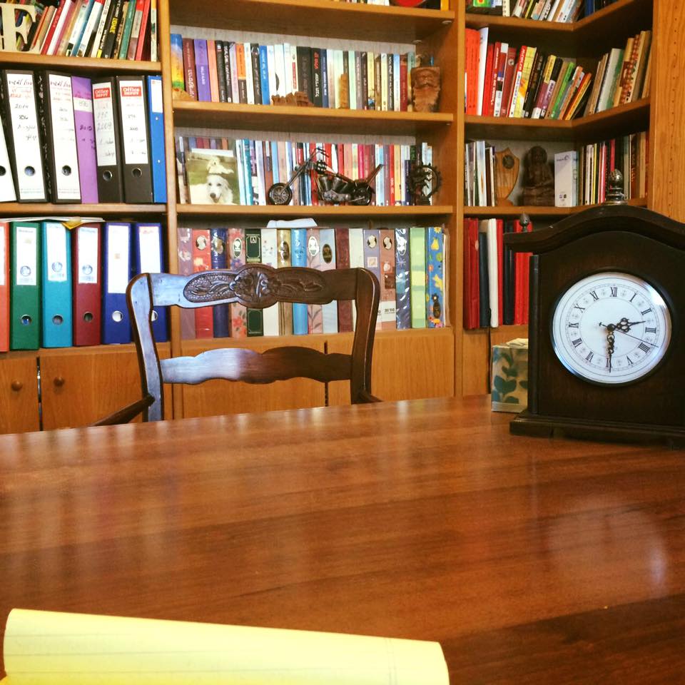 שולחן עץ עליו שעון מול ספרייה בחדר עבודה